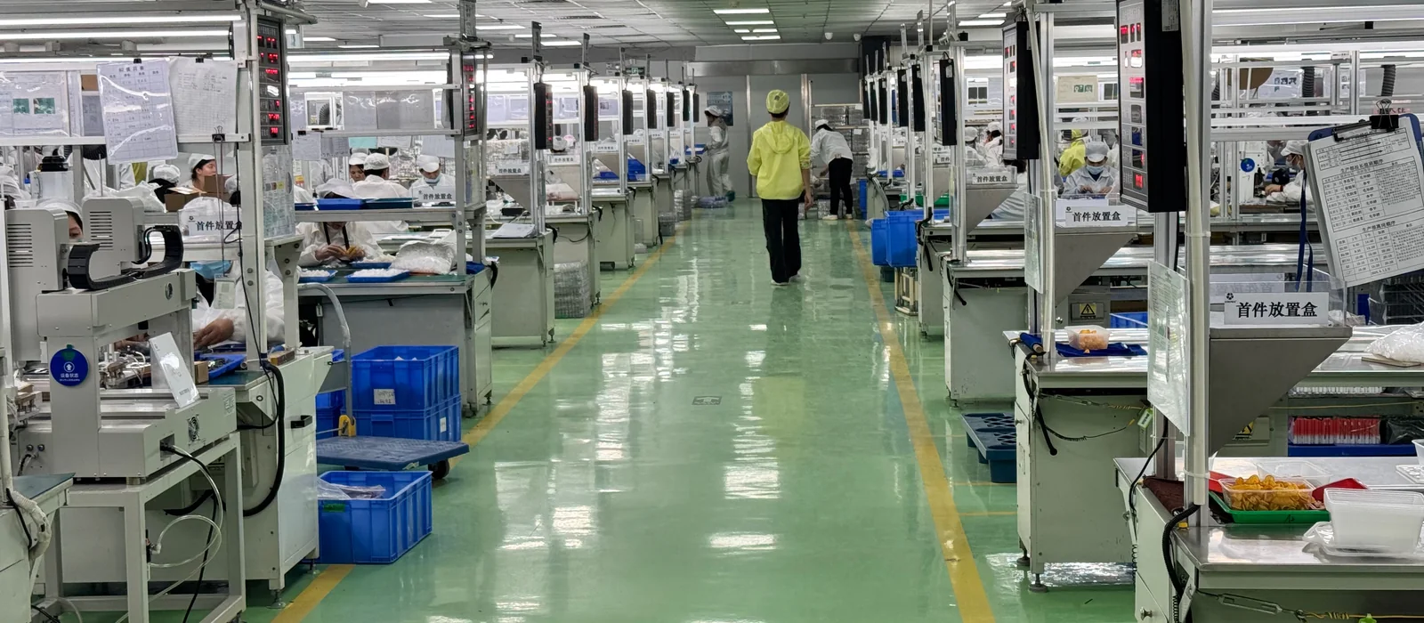 An assembly floor at a partner factory in Shenzhen, production lines running either side of a central aisle