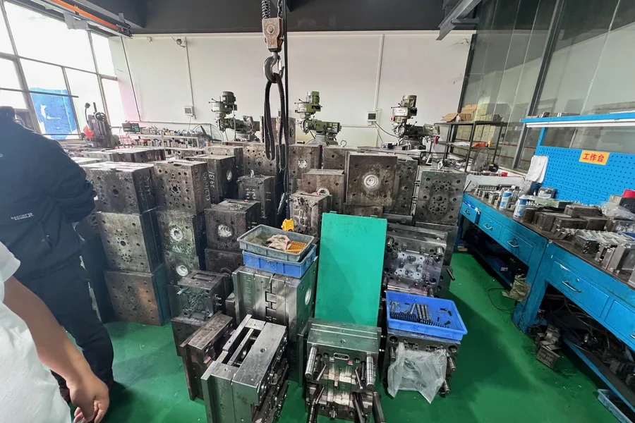 A tooling room stacked with steel injection molds beside milling machines