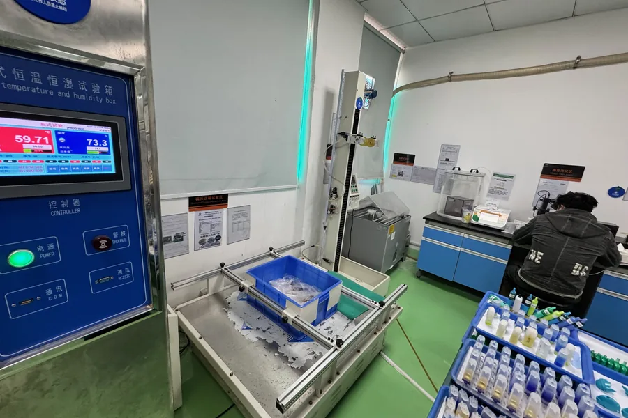 A temperature and humidity test chamber running at 59.71 degrees Celsius beside a transport vibration rig